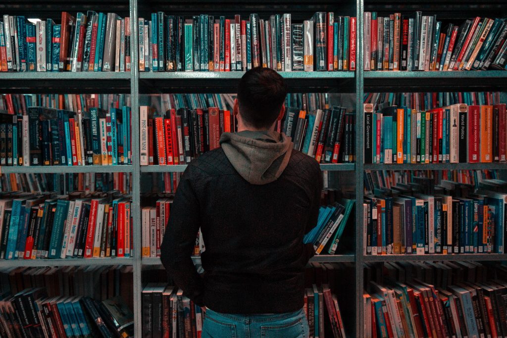 MAN STARING AT BOOKSHELF