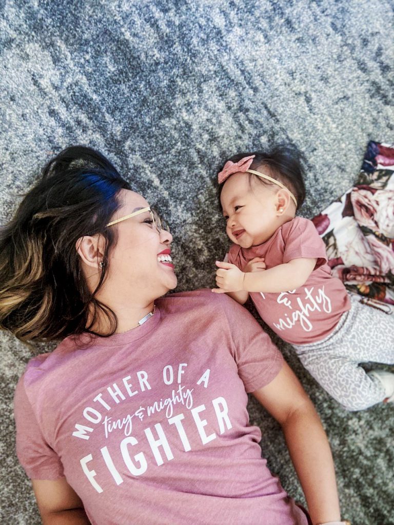 Mother and baby daughter smiling at each other.
