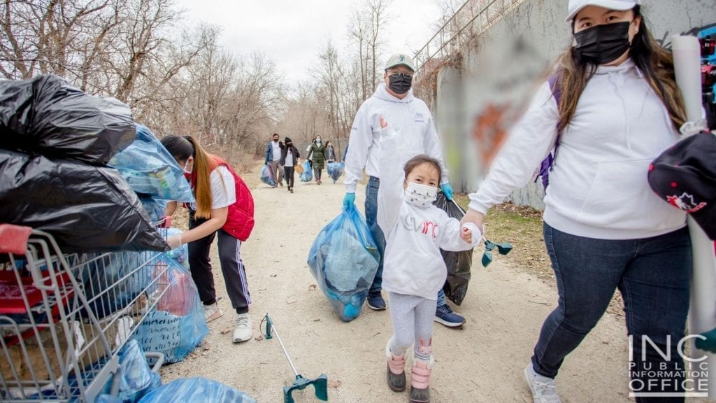 A 4 year old girl waves as she and her parents work with other Iglesia Ni Cristo (INC) or Church Of Christ volunteers during a 2-day Clean-up Drive activity of the Red River riverbank in Winnipeg, Manitoba.