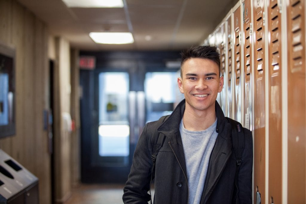 Young man leaning against lockers