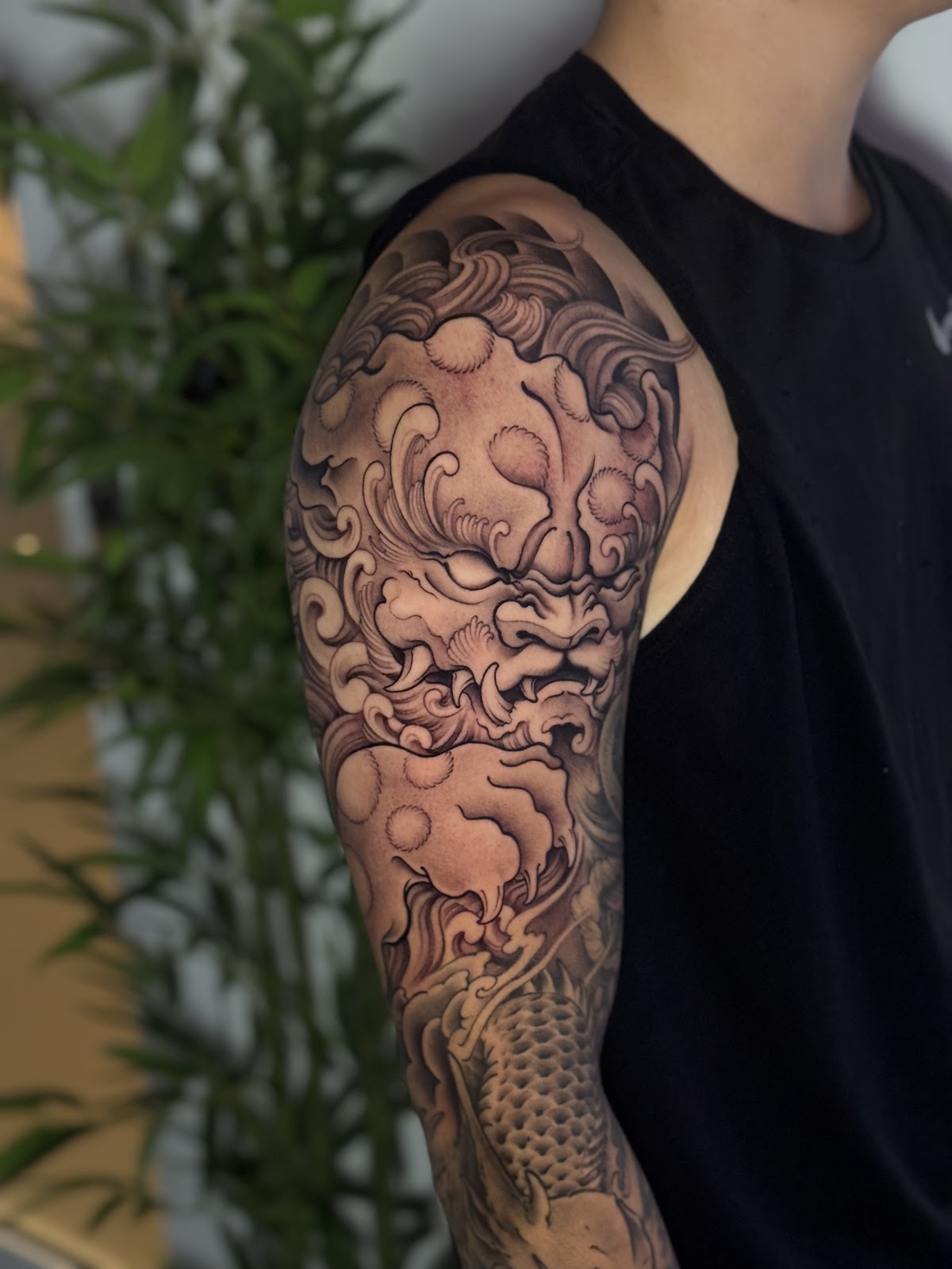 Detailed Japanese dragon tattoo with koi fish accents on the upper arm.