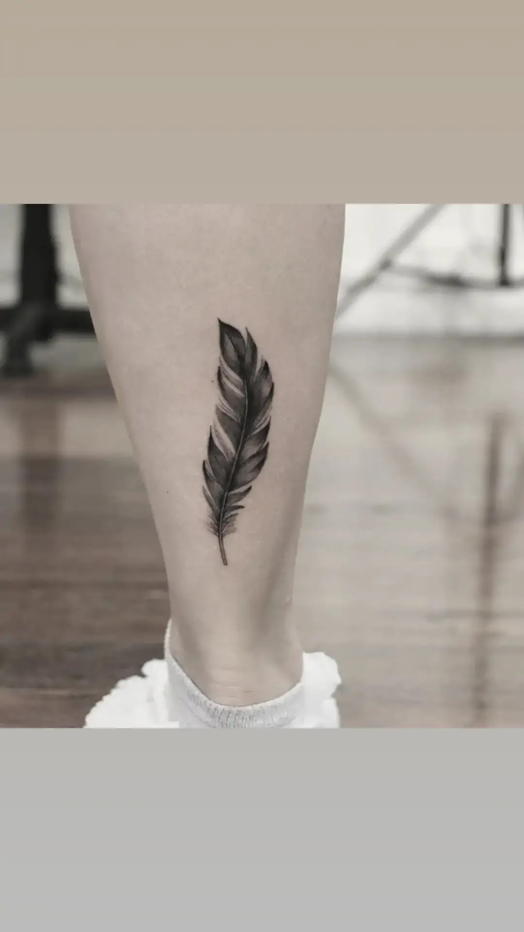 A delicate feather tattoo is showcased on the ankle.