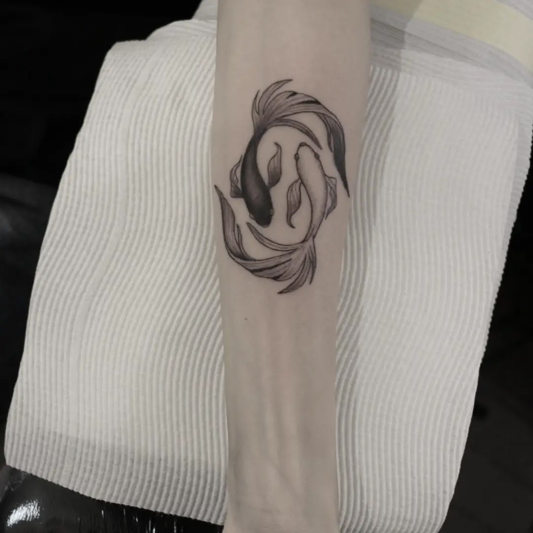 A detailed black linework koi fish tattoo on the forearm showcases a skilled Japanese style.