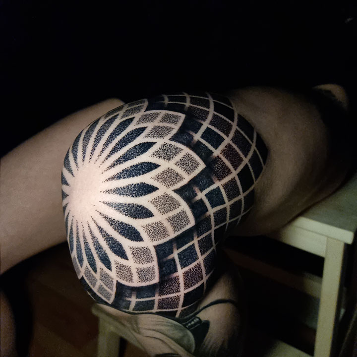 A captivating geometric dotwork tattoo with a central eye design adorns the forearm.