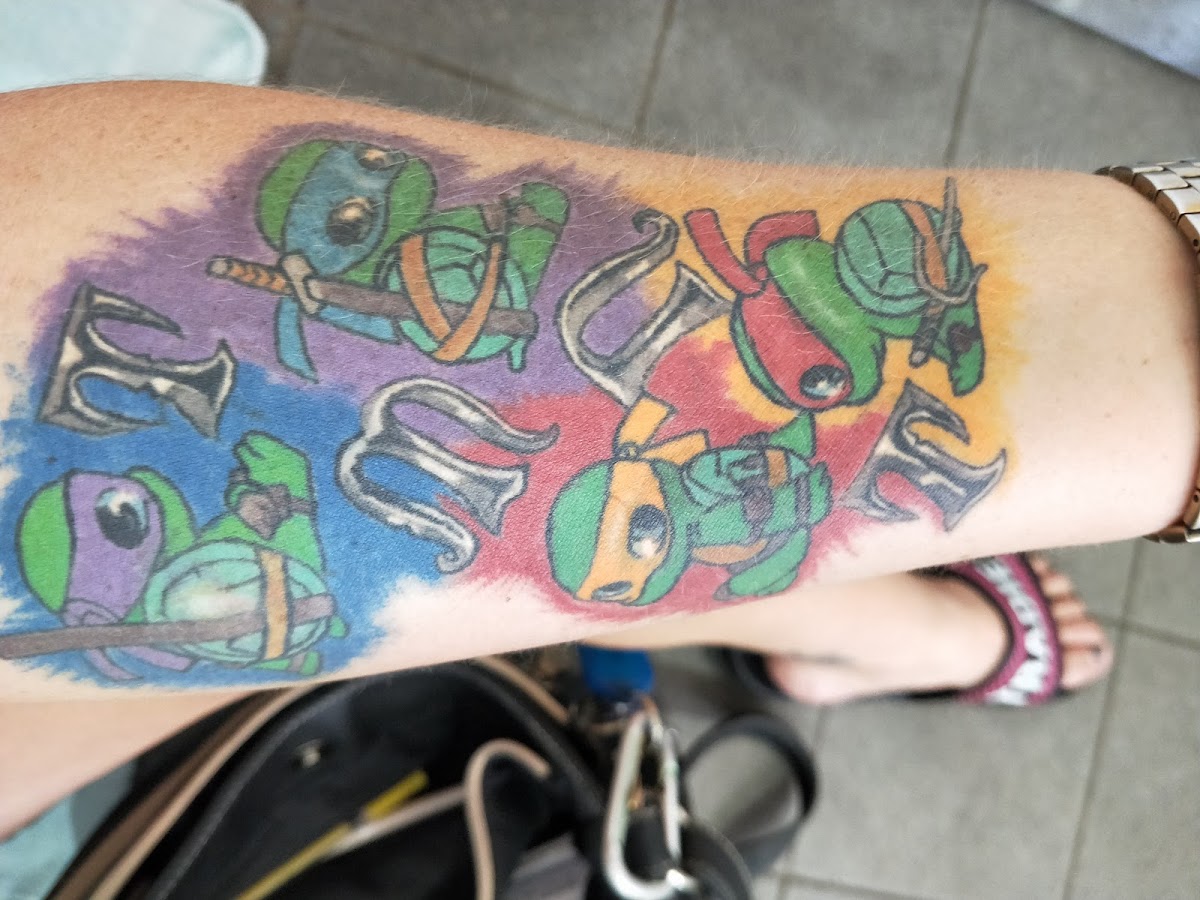A vibrant new school tattoo featuring Teenage Mutant Ninja Turtles on the forearm.