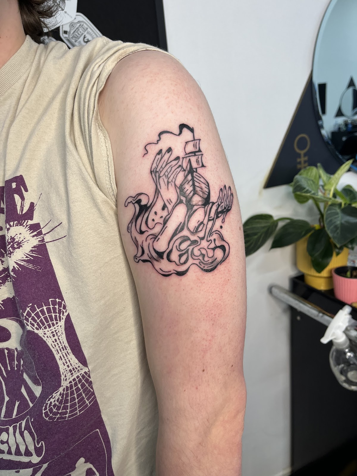 A detailed linework tattoo featuring an angel and skull design on the upper arm.