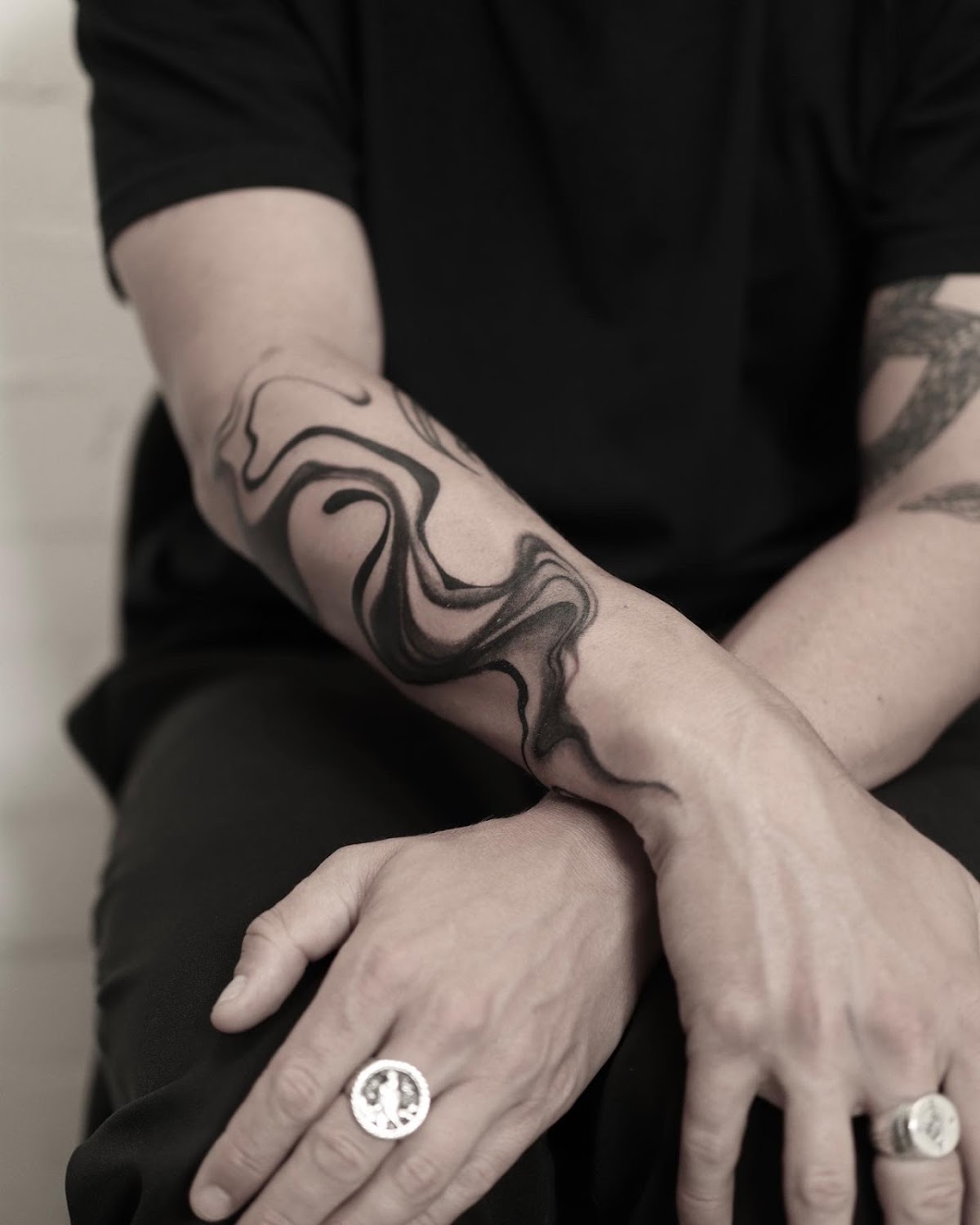 A striking black linework tattoo featuring abstract animal forms on the forearm.