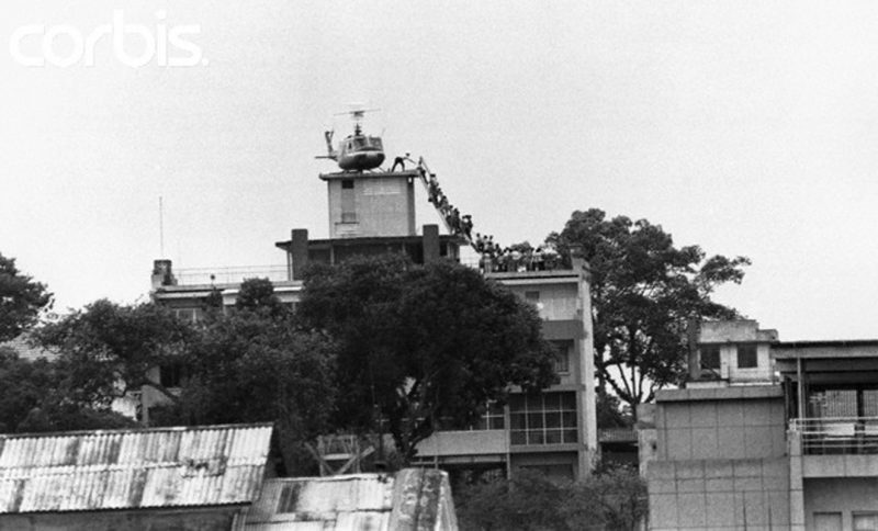 29 Apr 1975, Saigon, South Vietnam --- A CIA employee (probably O.B. Harnage) helps Vietnamese evacuees onto an Air America helicopter from the top of 22 Gia Long Street, a half mile from the U.S. Embassy. --- Image by © Bettmann/CORBIS