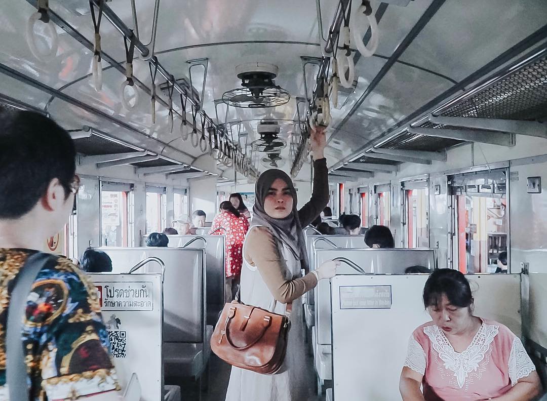A girl traveling to Thailand and posing inside a train