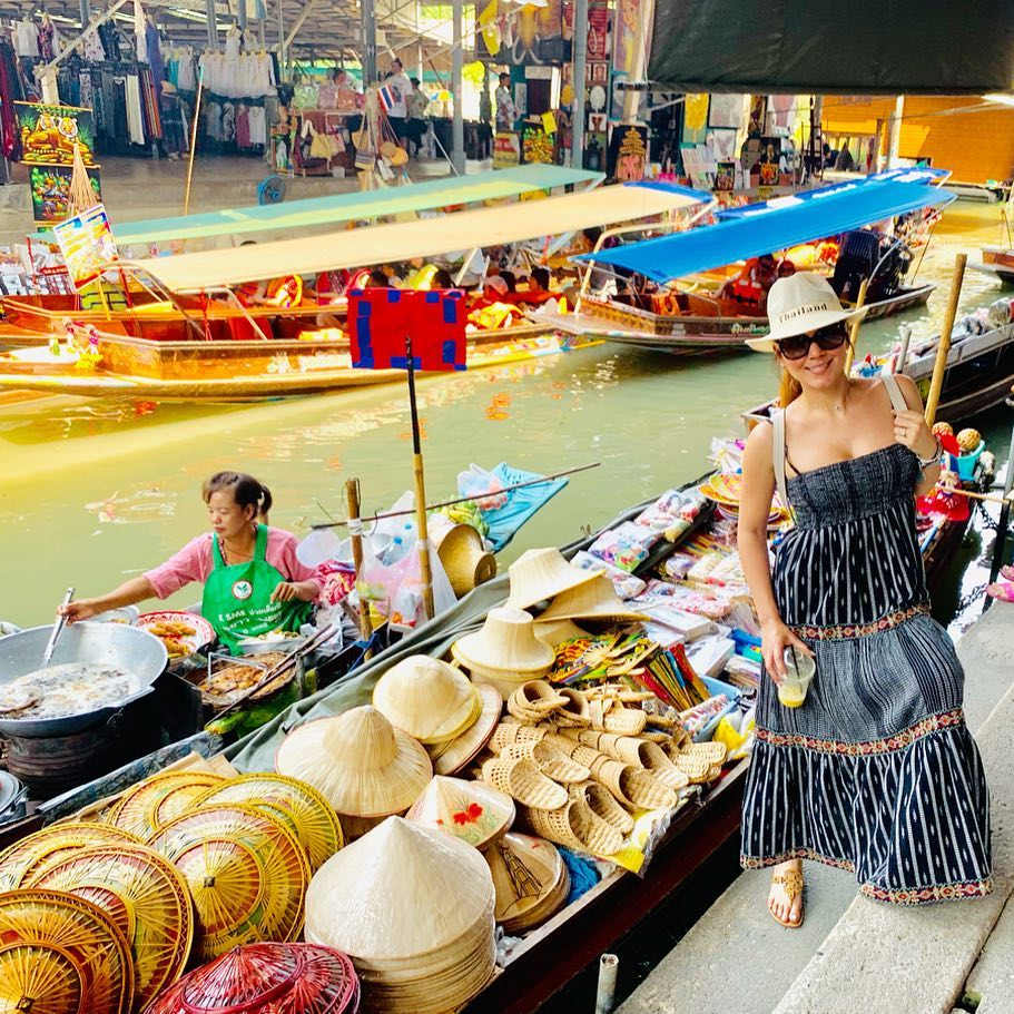 A female tourist posing near a souvenir boat in a floating market