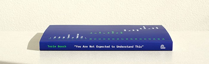 A photo of the cover of “You Are Not Expected To Understand This”; it is blue and lying on its side, with the spine facing the viewer. The editor’s name, Torie Bosch, is in a green monospaced font; the title is in a white monospaced font