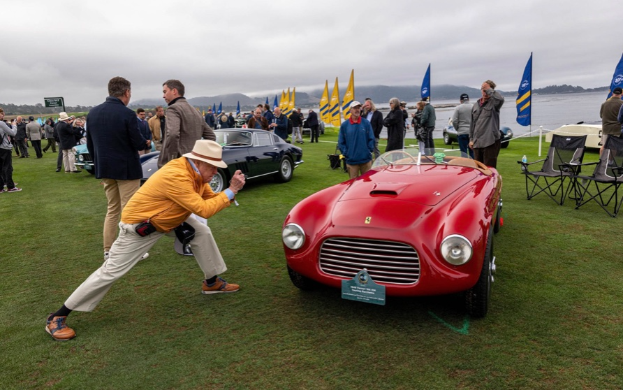 A visitor photographs a 1948 Ferrari 166 MM Touring Barchetta