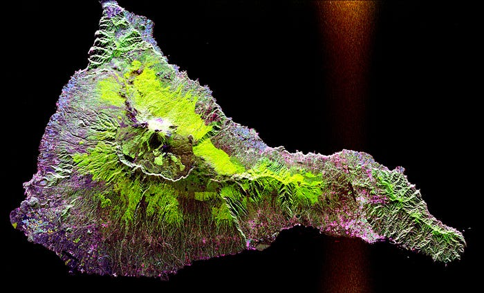 This radar image acquired by the SIR-C/X-SAR radar on board the Space Shuttle Endeavour shows the Teide volcano. The city of Santa Cruz de Tenerife is visible as the purple and white area on the lower right edge of the island. Lava flows at the summit crater appear in shades of green and brown, while vegetation zones appear as areas of purple, green and yellow on the volcano’s flanks. Source.