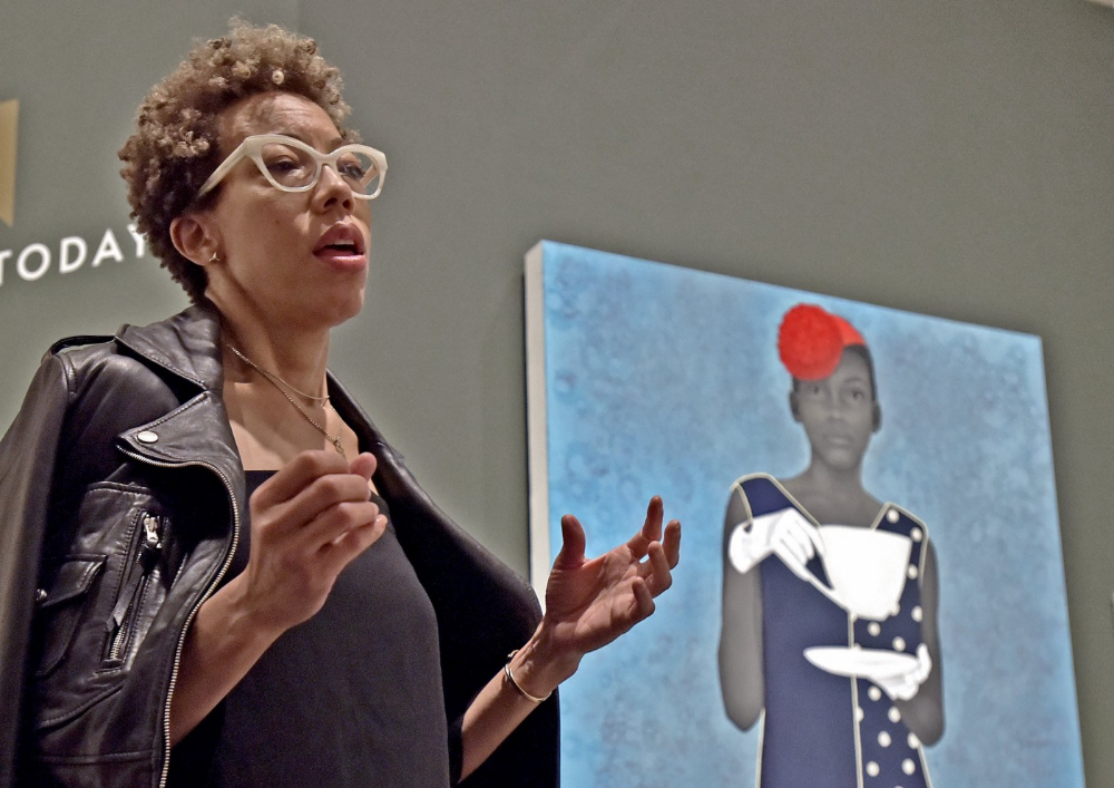 Amy Sherald speaking about her work in front of her painting “Miss Everything (Unsuppressed Deliverance) | Getty Images
Raleigh News & Observer / Contributor May 2018