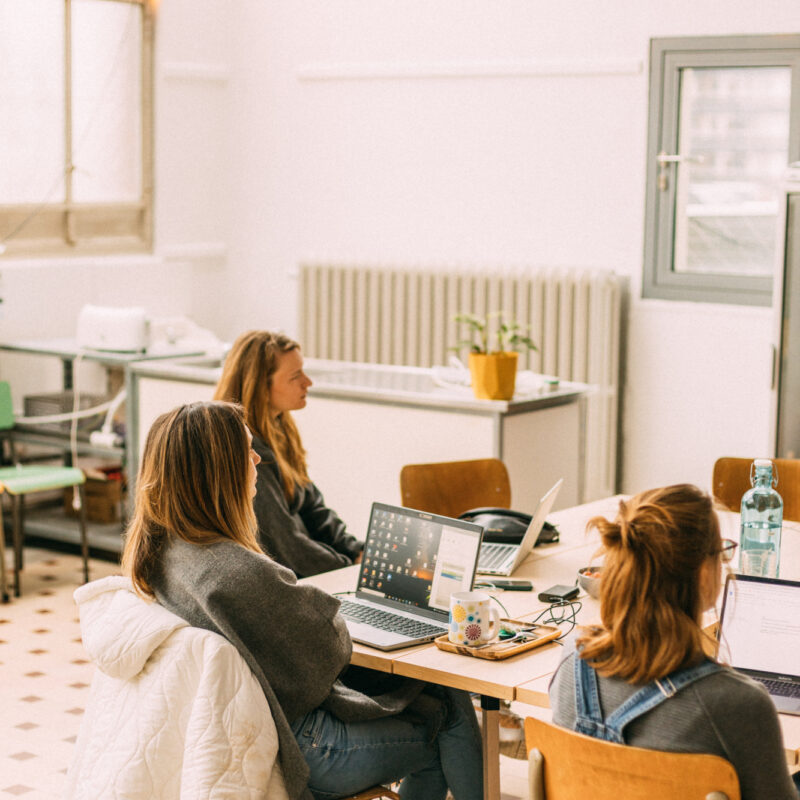 3 vrouwen volgen een opleiding en zitten aan tafel met een laptop