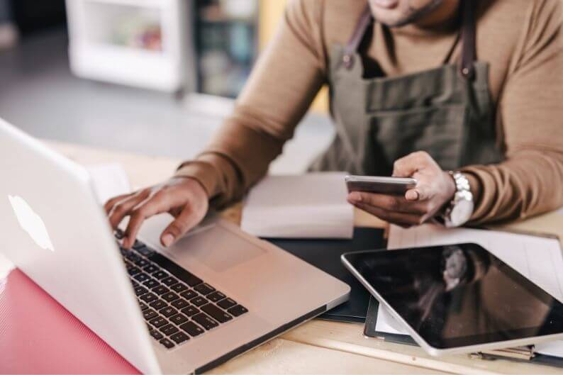 A franchise owner researches funding options for his business on a laptop.