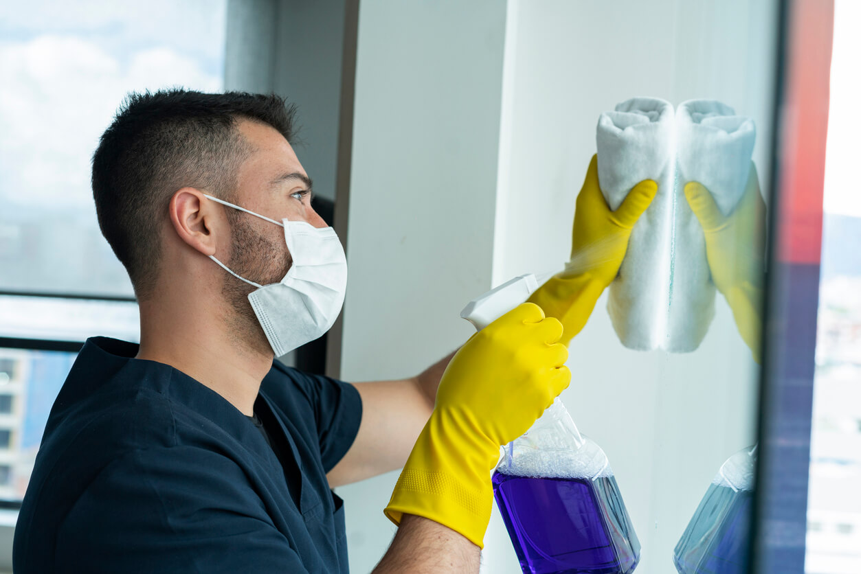 Commercial Cleaning Franchise | A man in a mask uses a disinfectant cleaning solution to clean office surfaces.