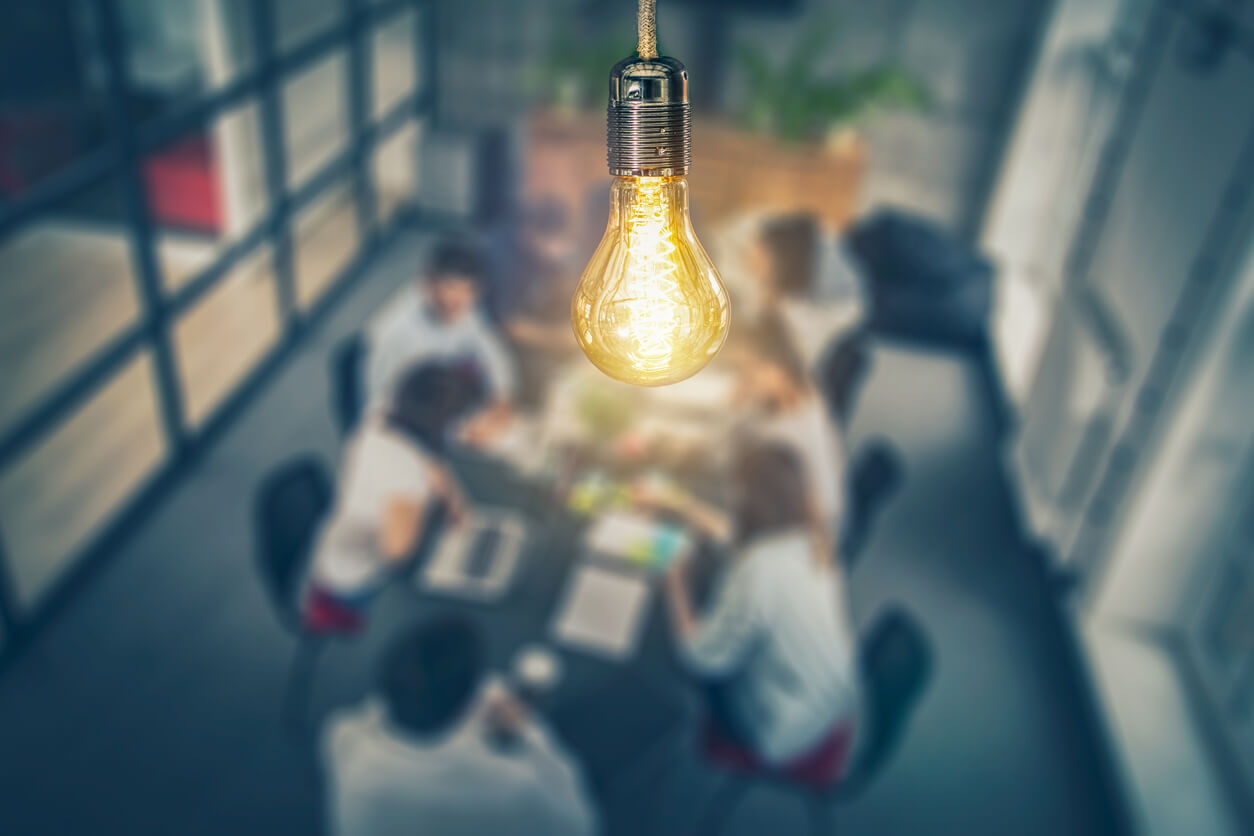 A group of stakeholders gathers around a conference room table.