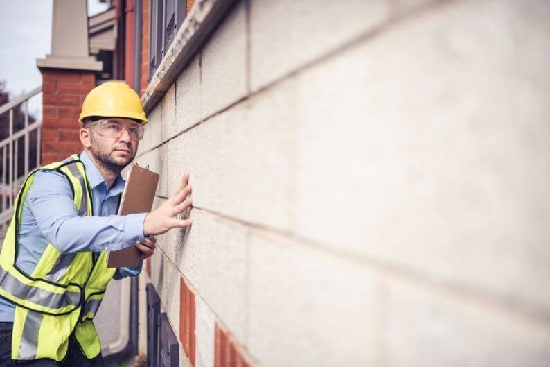 Building inspector examines structure's wall at construction site