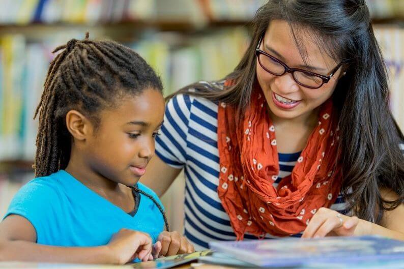 Tutor helps a young female student with homework.