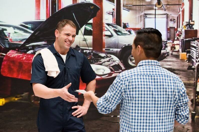 Mechanic works with a customer at automotive franchises garage