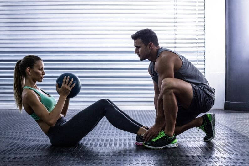 Personal trainer who works for one of the popular home-based franchises helps a client correct her form.