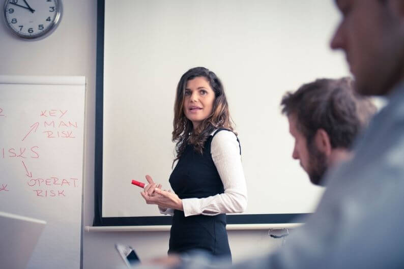 Woman teaches business students about business risks and how to mitigate them.