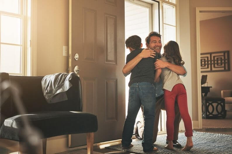 Father who has discovered how business owners can find balance at work is welcomed home by his children after a day at the office.