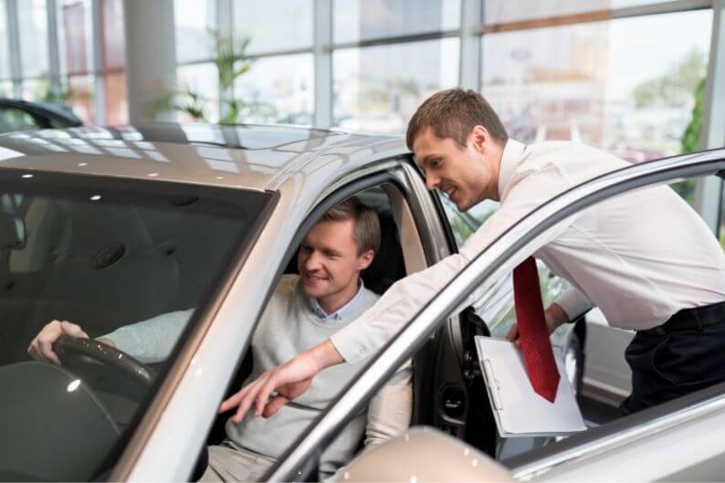 A car salesman shows off his product to a potential customer.