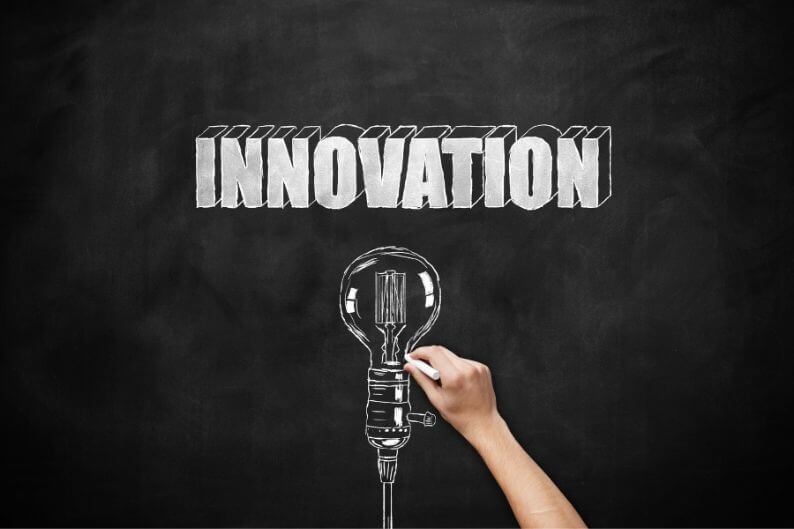 "Innovation" written on a chalkboard along with a light bulb illustration