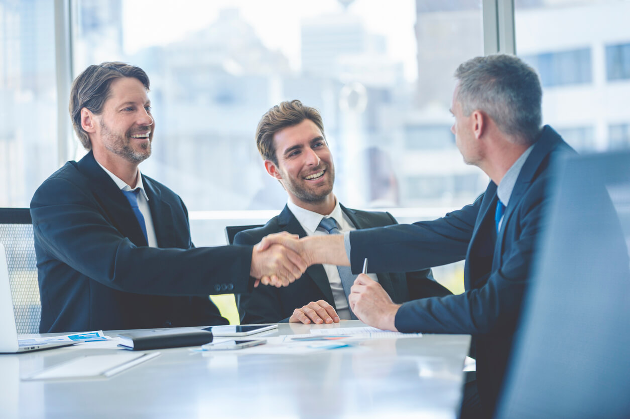 Business partners shaking hands at a conference table.