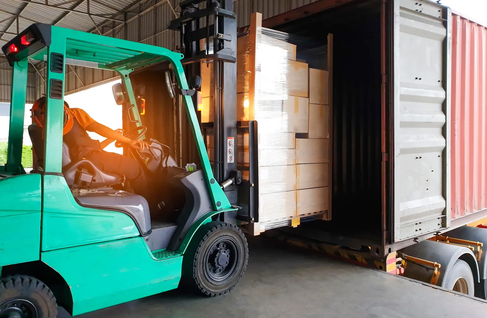 Carrello elevatore che scarica scatole da un container.