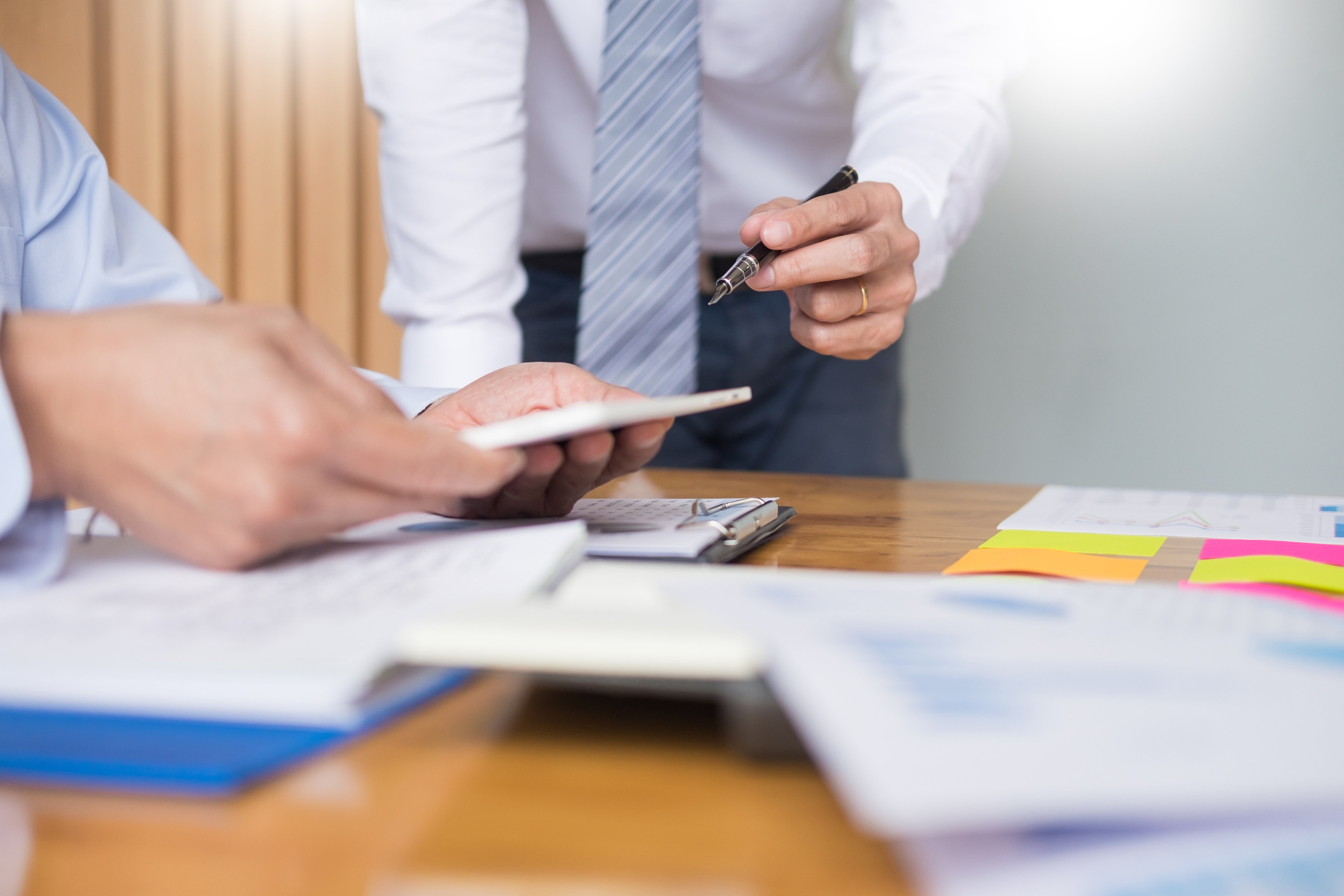 Uomini d'affari al lavoro su documenti e grafici a una scrivania.