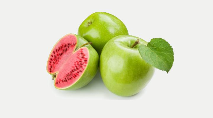 Tre mele verdi, una tagliata a metà con l'interno rosa.