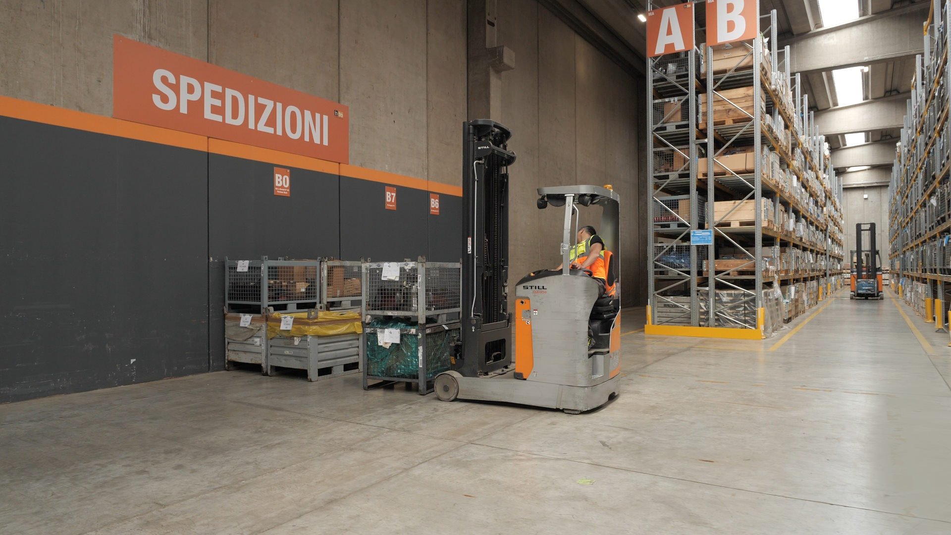 Operaio al lavoro in un magazzino con un carrello elevatore.