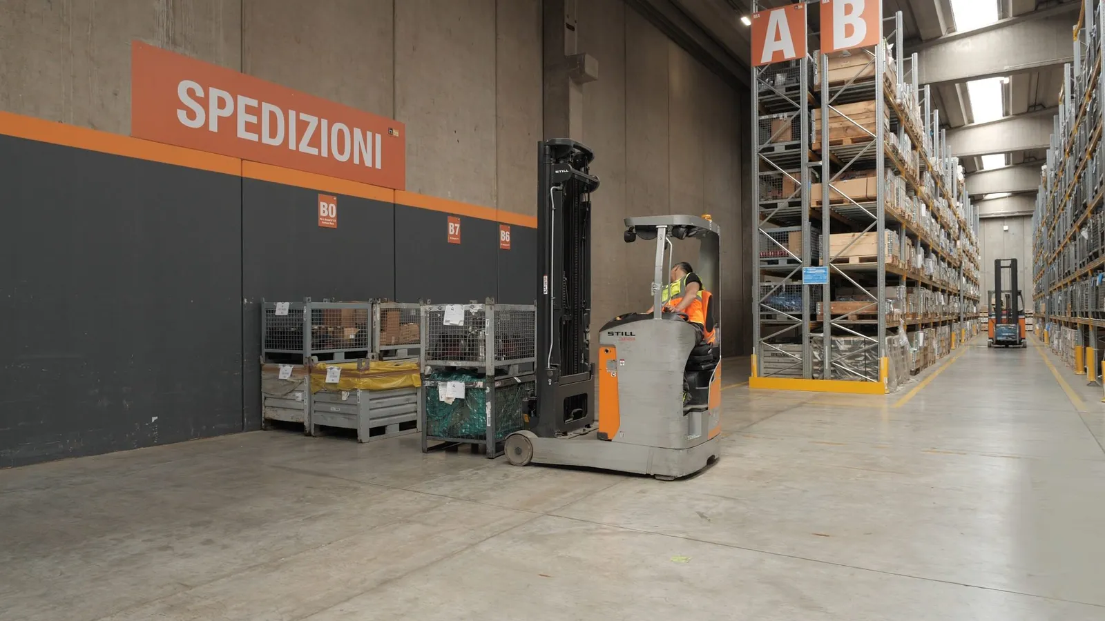 Operaio al lavoro in un magazzino con un carrello elevatore.