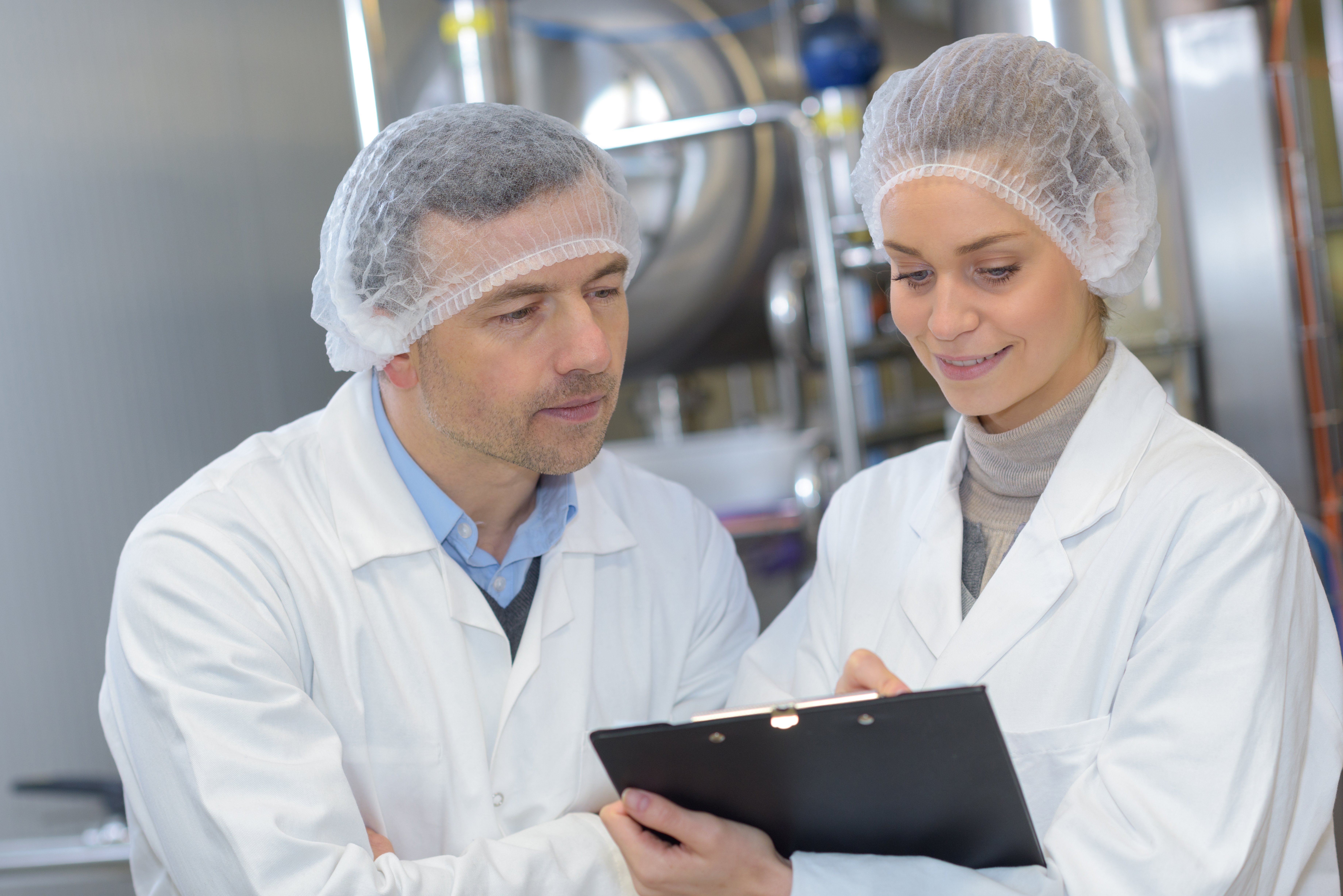 Due scienziati che indossano camici da laboratorio esaminano una cartella con appunti.