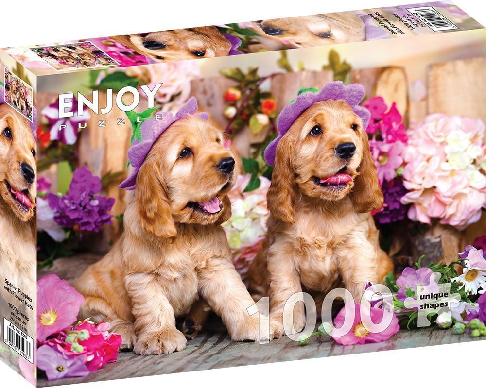 Two golden spaniel puppies wearing purple flower hats sitting among pink and purple flowers.