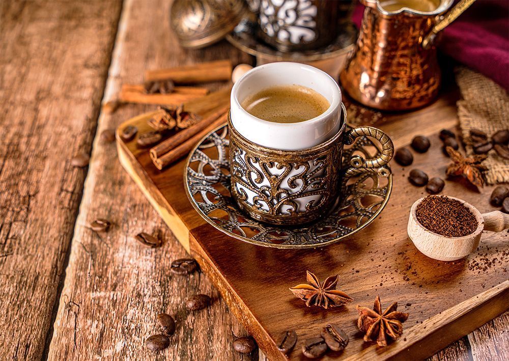 A cup of Turkish coffee with spices and coffee beans on a wooden board