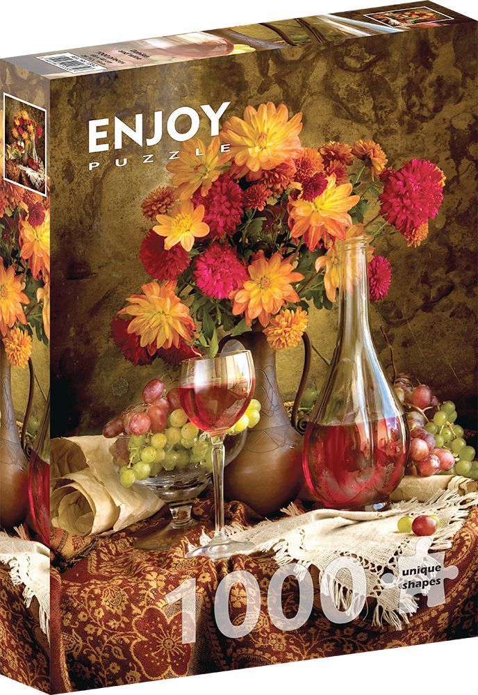Still life with a bouquet of orange and red dahlias, a glass of wine, a decanter, and green grapes on a textured cloth.