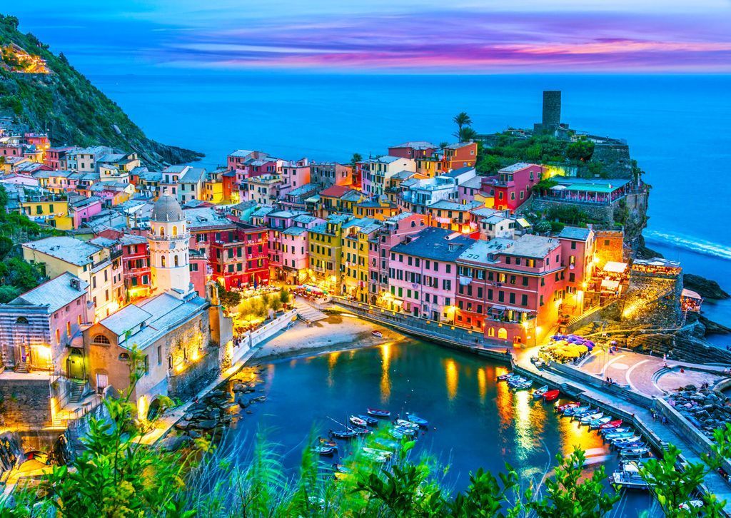 Coastal Italian village of Vernazza at twilight with warm lights reflecting in the harbor