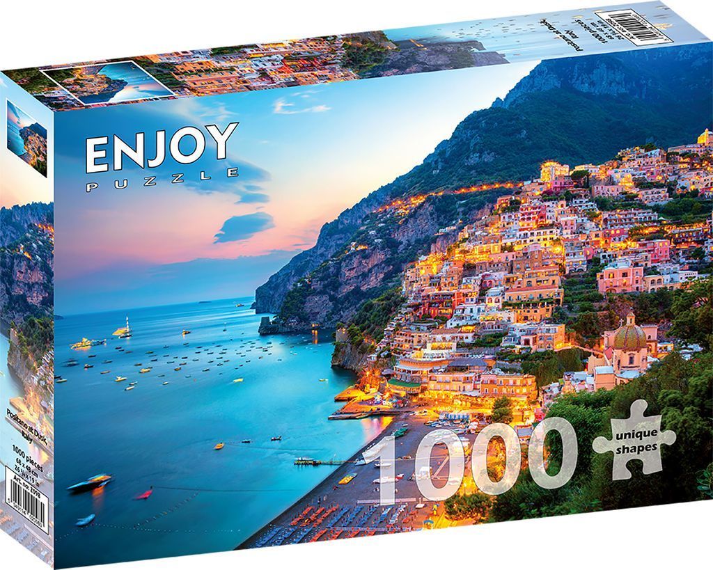 A twilight view of Positano, Italy, featuring cliffside houses glowing along the coast above a boat-filled bay.