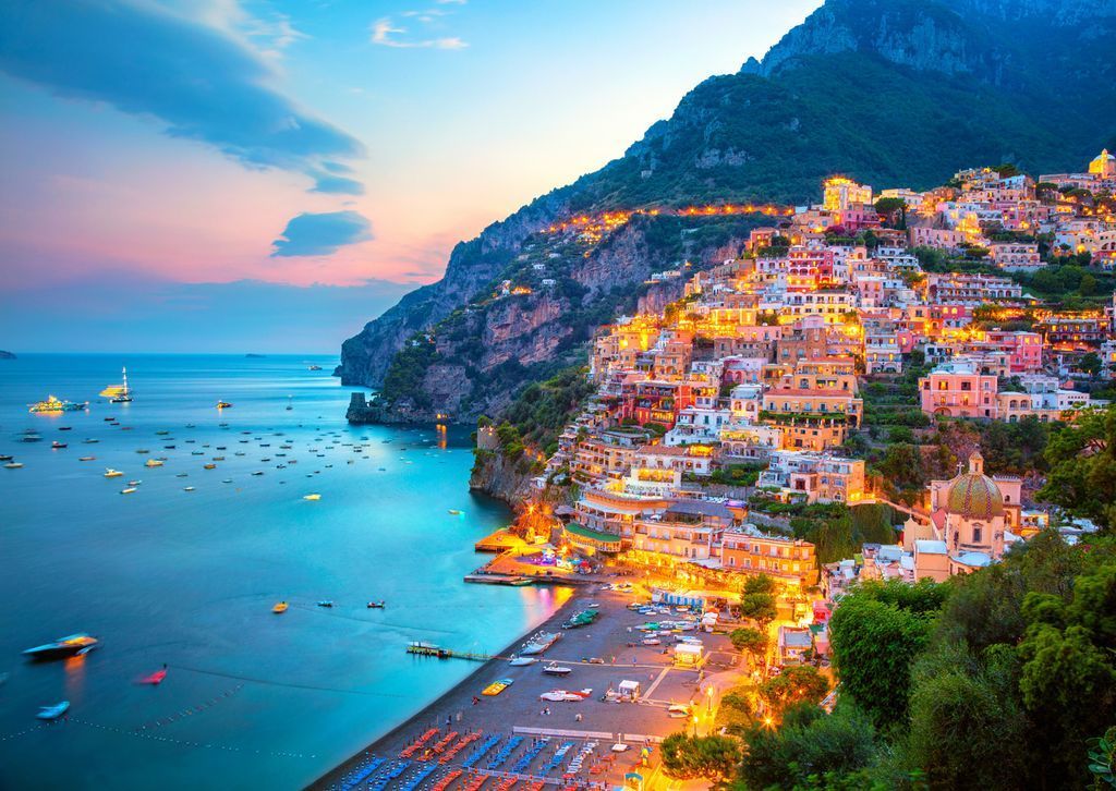 Coastal Italian town of Positano at twilight with warm lights against a blue dusk sky