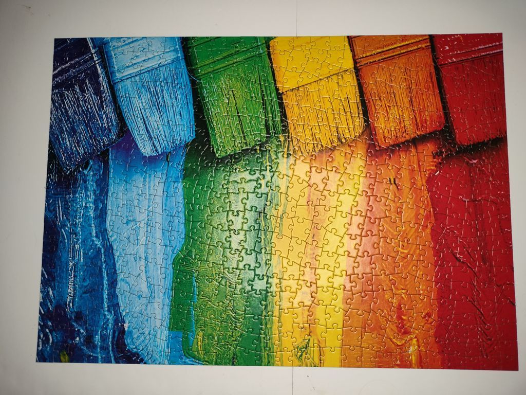 Six paint brushes lined up horizontally with thick strokes of rainbow-colored paint trailing down.