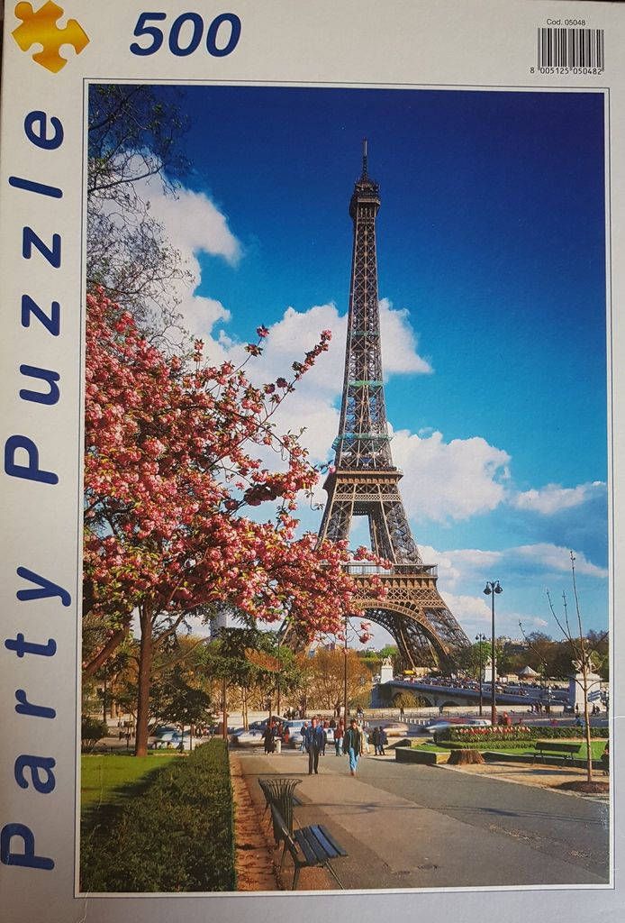 The Eiffel Tower in Paris framed by blooming pink cherry blossom trees under a bright blue sky.