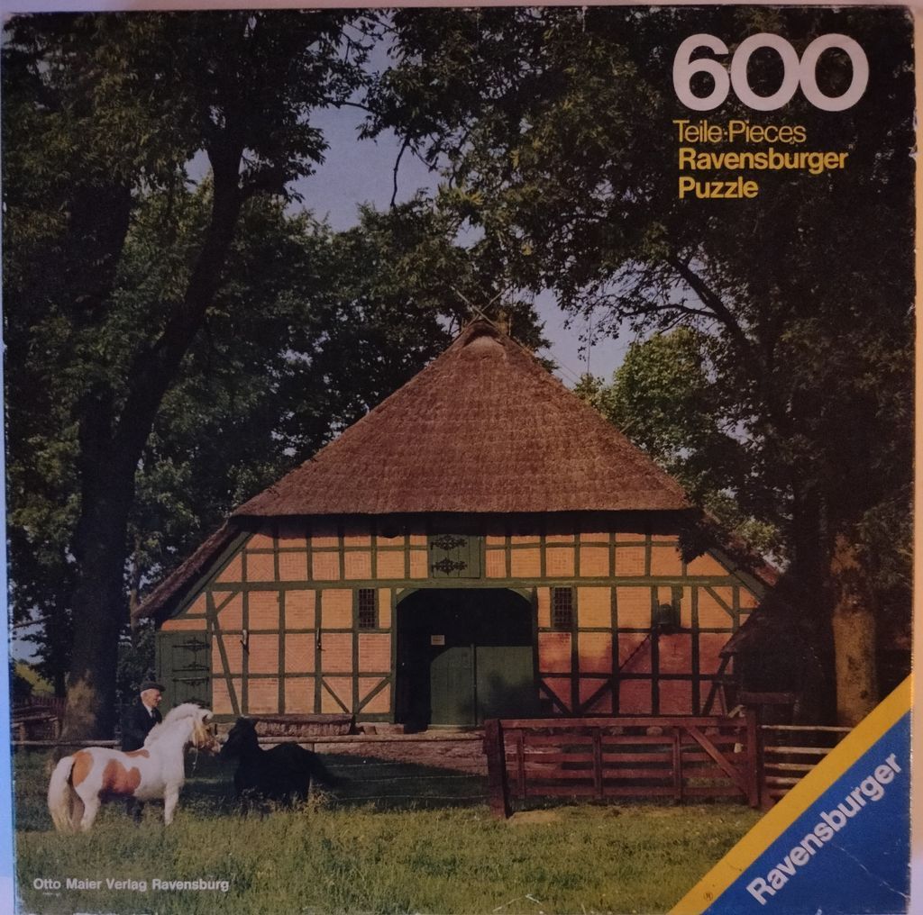 A photograph of a traditional timber-framed barn with a thatched roof, featuring an elderly man and two ponies in front.