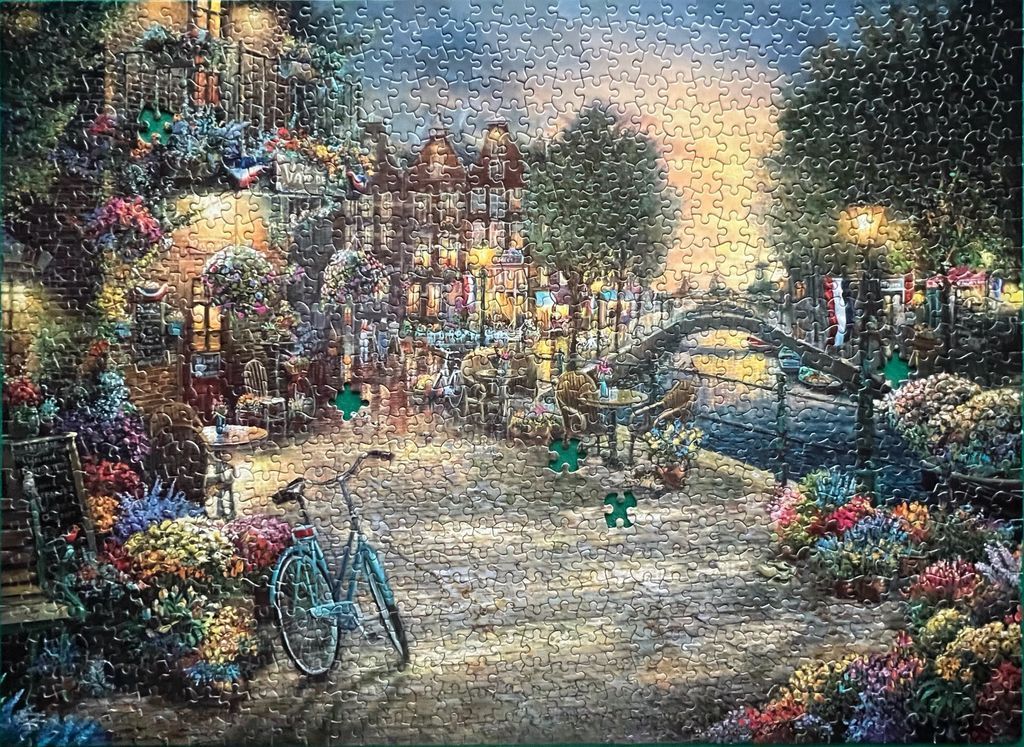 A charming, warm-toned European canal-side cafe scene with flowers and a bicycle.