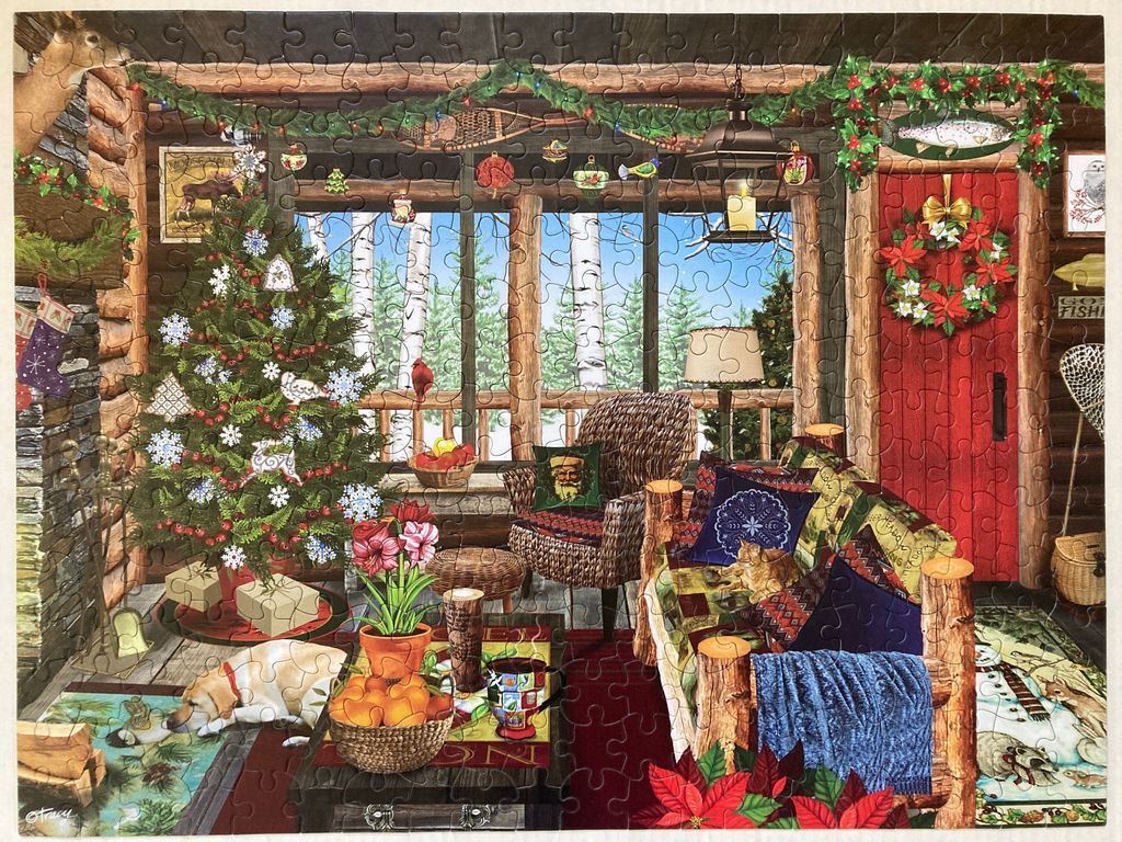 Cozy rustic cabin interior decorated for Christmas with a lit tree, a dog on the floor, and a view of a snowy forest.