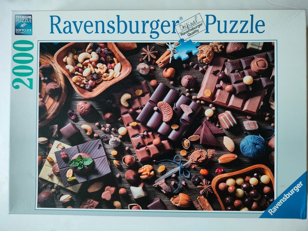 Top-down view of an assortment of chocolates, nuts, and dried fruits arranged on a dark wooden surface.