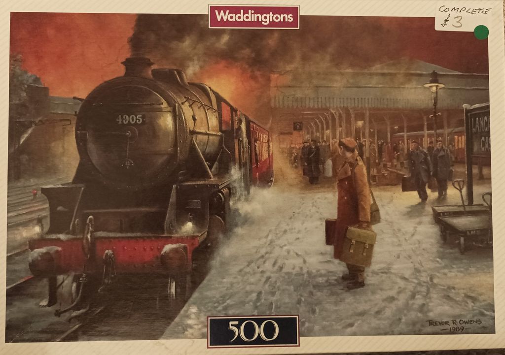 A steam locomotive pulling into a snowy train station platform at dusk, with passengers waiting on the platform.